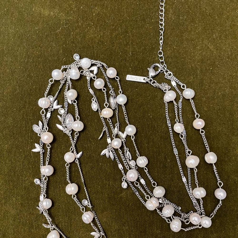 A thin 20” long 2-themed necklace. One necklace has a pearl like design and…